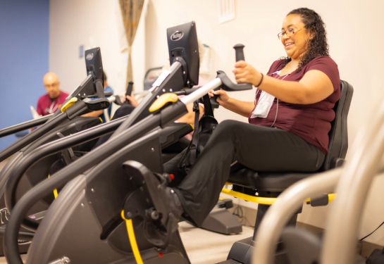 A patient exercises on a seated cardio machine during a cardiac rehabilitation session.