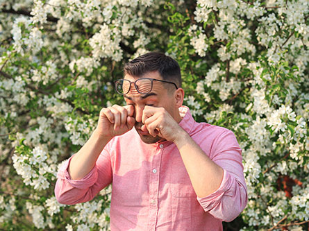 man with seasonal allergies rubbing his eyes