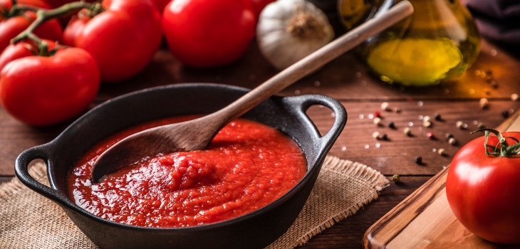 A bowl of tomato sauce with a wooden spoon.