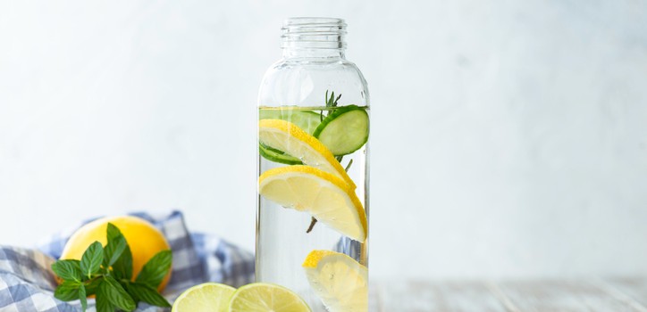 A glass bottle of water with lemon and lime slices