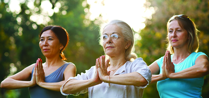 Three women doing yoga outdoors.