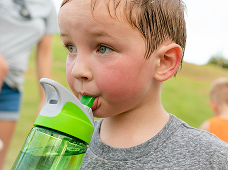 A little boy drinking from a water bottle featured