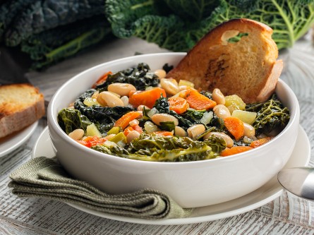 A bowl of beans with greens and side of bread.