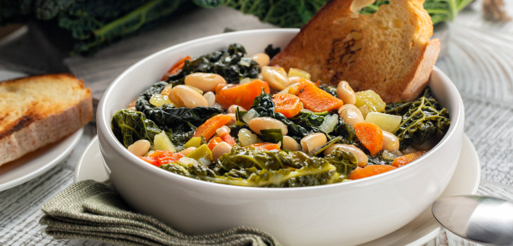 A bowl of beans with vegetables and greens