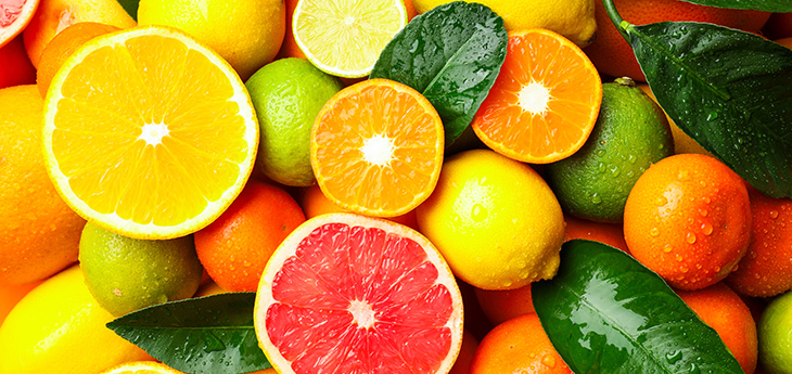 Different ripe citrus fruits and leaves with water drops
