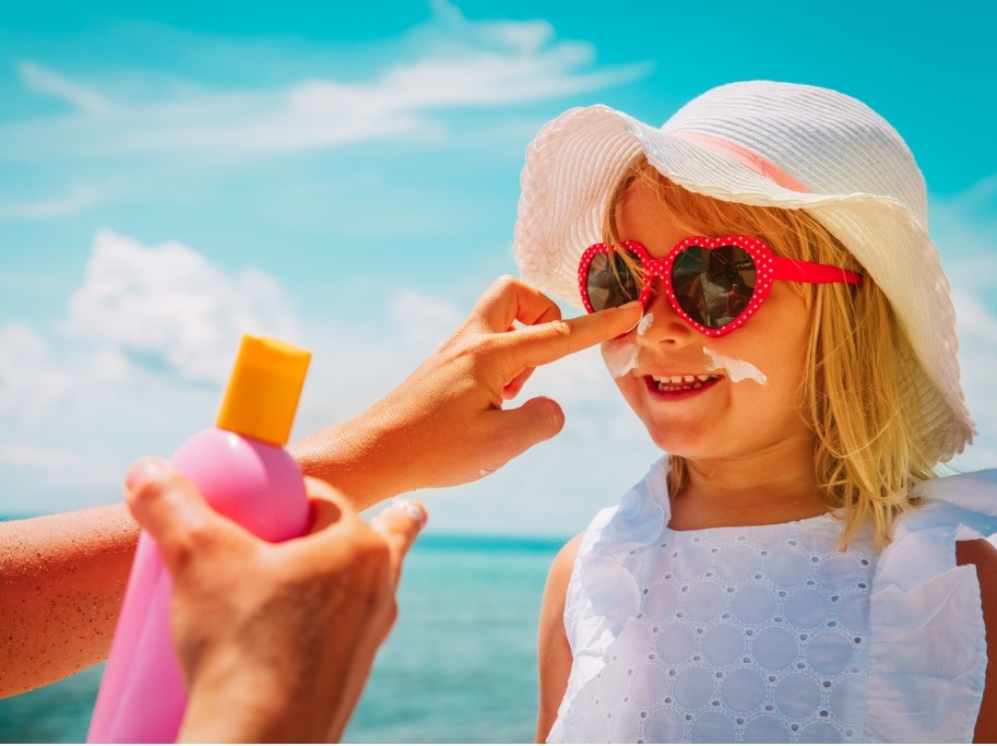 person applying sunscreen to childs nose