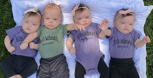 Quadruplets laying on a blanket outside
