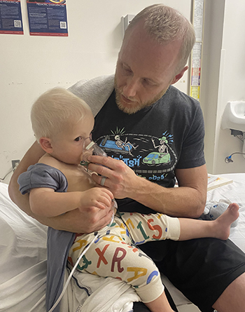 Shea receiving a breathing treatment with her dad in the hospital