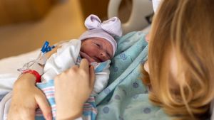 Mother holding her newborn baby in a hospital bed.