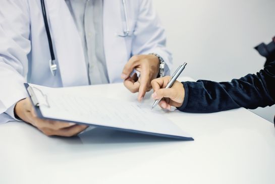 patient signing paper with doctor