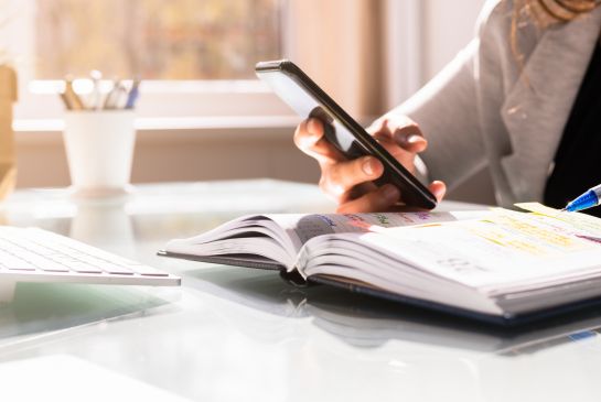 person holding cellphone on top of a book