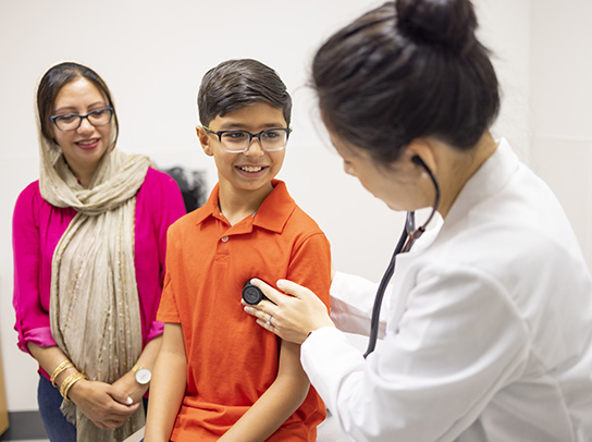 Un médico utilizando un estetoscopio para escuchar el corazón de un paciente pediátrico