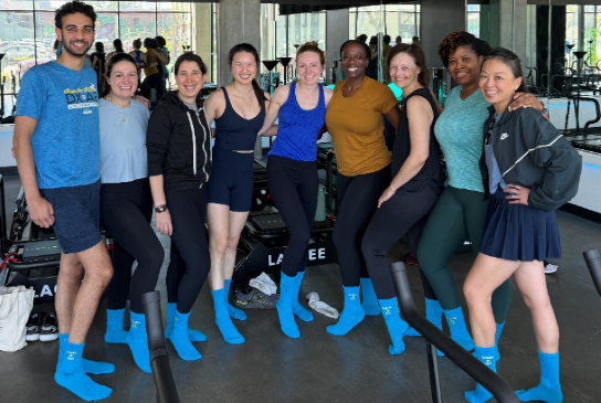Department members posing for a photo in a pilates studio with matching blue socks