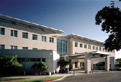 Lawrence J. Ellison Building shown from the street under a clear blue sky.