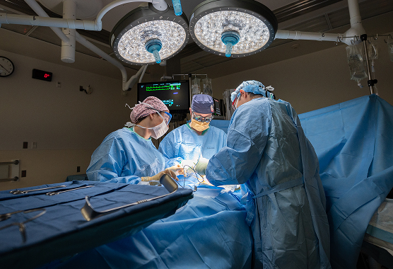 Two surgeons in masks and scrub caps perform a procedure in an operating room.