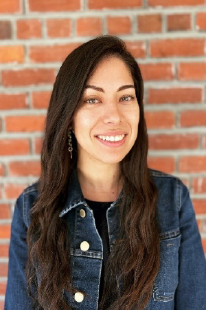 Headshot of Casey smiling in front of red brick wall