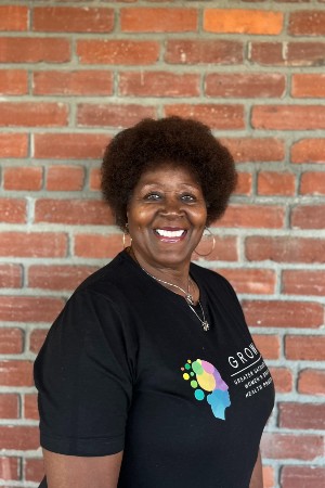 Headshot of Flossie smiling in front red brick wall