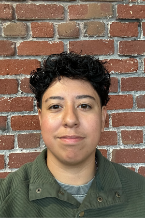 Headshot of Lyndsey smiling in front of red brick wall