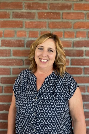 Headshot of Michelle smiling in front of red brick wall