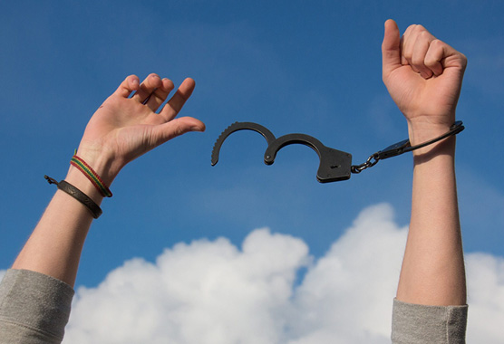 Hands waving in the air with handcuffs coming off. 