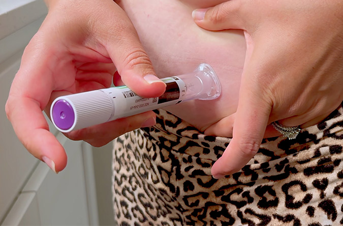 Woman administering GLP-1-based injection to her abdomen.