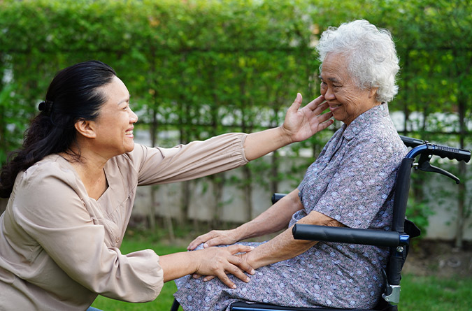 Younger woman next to older woman in wheelchair.