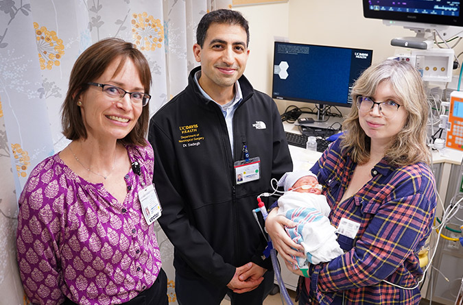 Maternal-fetal medicine specialist Leanna Sudhof, neurosurgeon Cameron Sadegh, and smiling patient holding her baby.