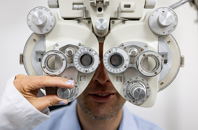 A man sitting for an eye exam with a phoropter. 