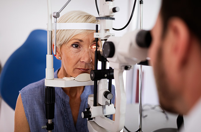 A woman getting eye exam using a slit lamp.
