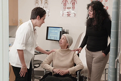 A doctor speaking to a patient who is sitting in a wheelchair