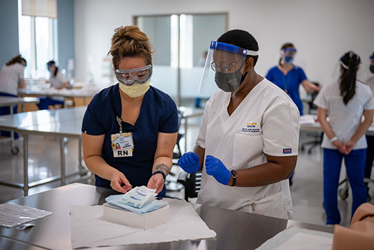 Two medical professionals with protective masks and eyewear opening a medical kit.