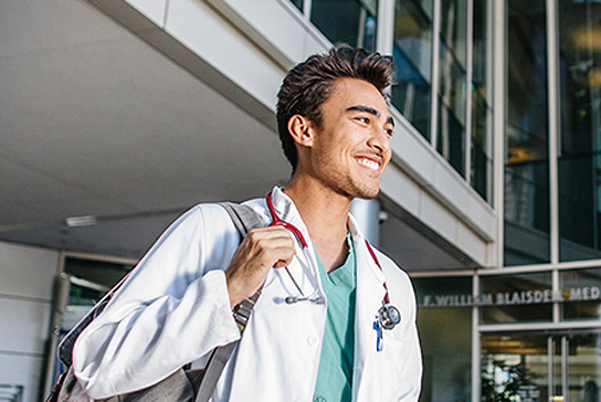 Medical professional walking in front building.