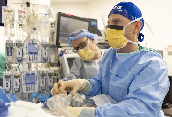 Two anesthesiologists working in a surgery room with medical monitors and equipment.