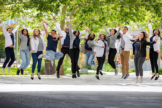Multiple people jumping into the air cheerfully.