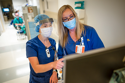 Two care team members consult a computer in the clinic hallway