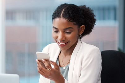 A professional woman smiles during a telehealth video visit from her office on a hand-held smartphone