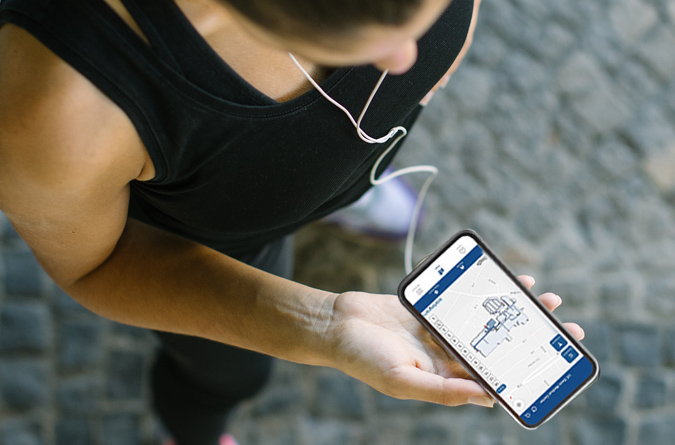 A woman holding a smart phone displaying the find my way app.