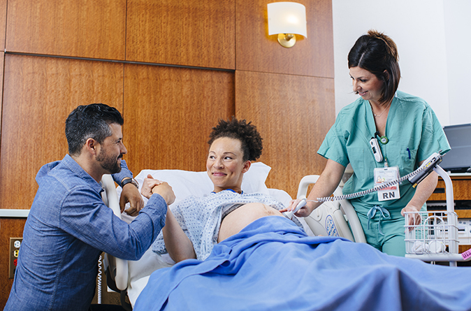 A support person with an expecting patient and her provider in the hospital's birthing suites