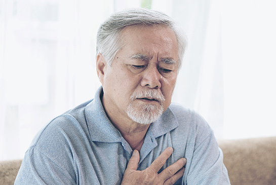 A middle-aged Asian man clutches his chest