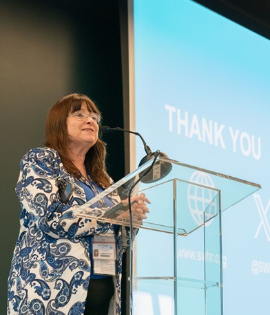 professional image of a woman in a paisley jacket speaking at a podium