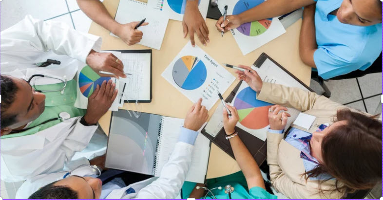 overhead shot of table with seated people comparing charts
