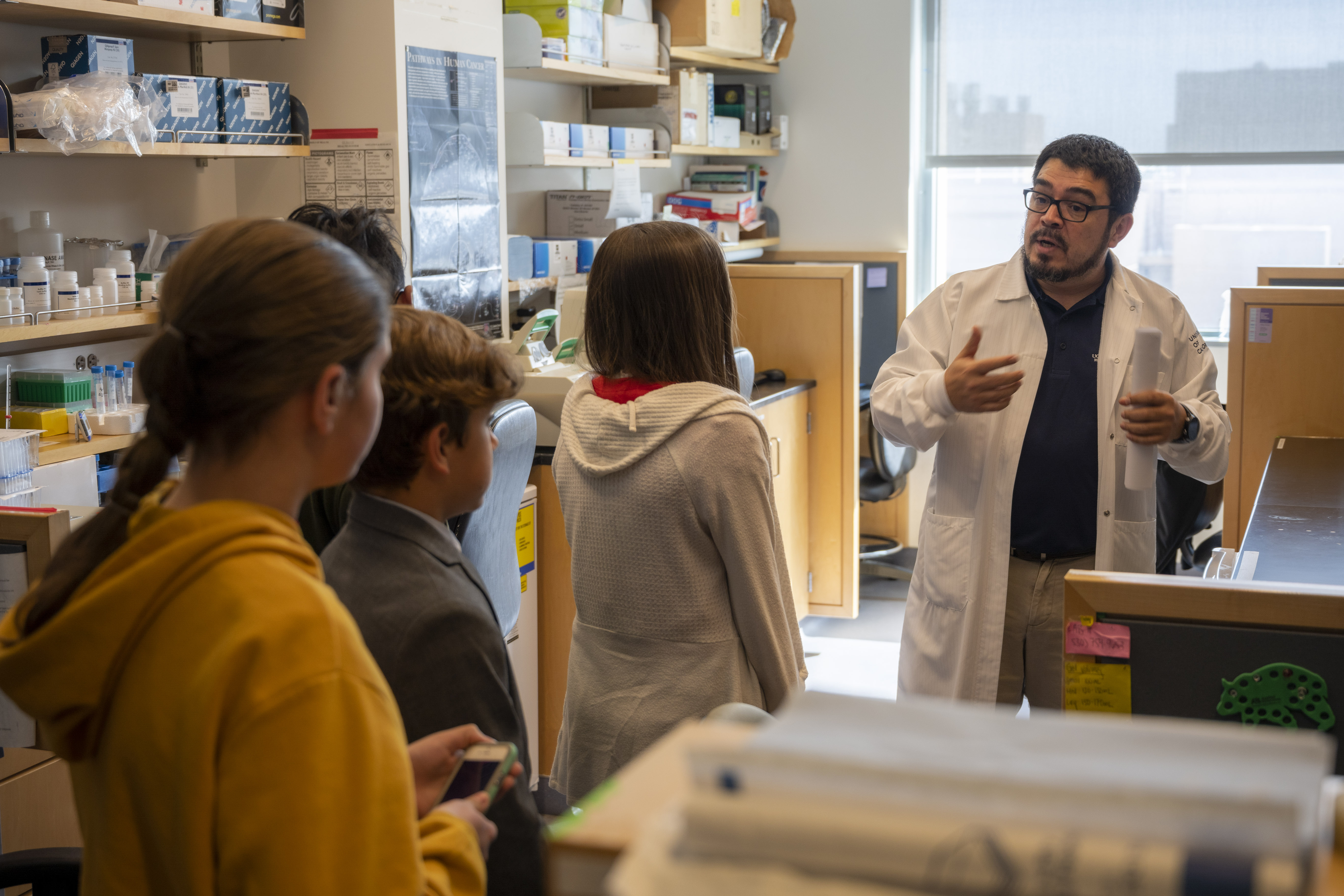 A physician interacts with pre-teen students in a laboratory
