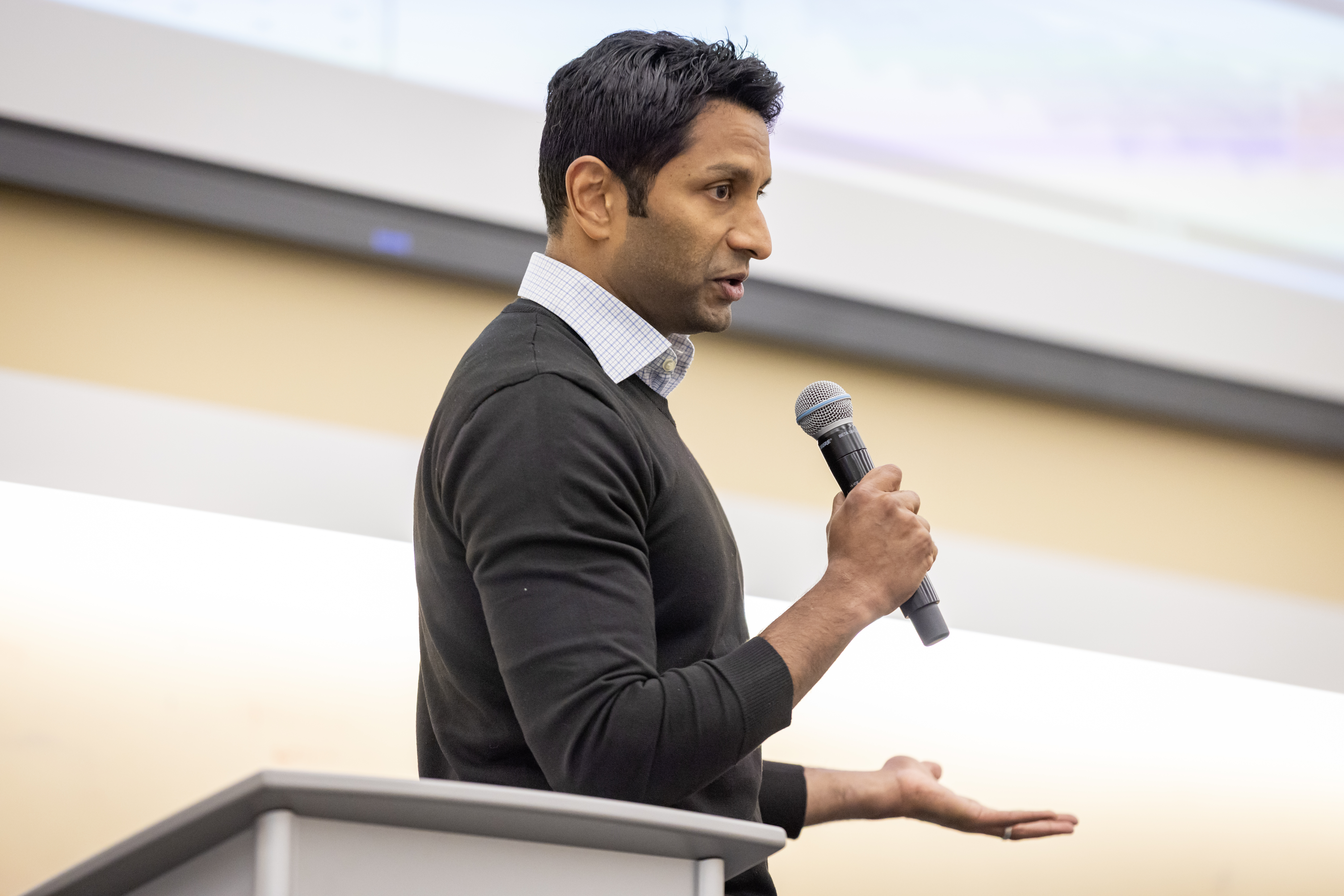 man stands next to lectern with a microphone