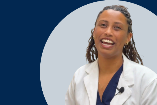 A woman wearing a white medical coat speaks to the camera against a light gray circular background with a navy blue backdrop.