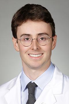 Portrait of medical student Aidan O'Brien in white coat and smiling
