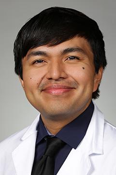 Portrait of medical student Irvin Reyes in white coat and smiling