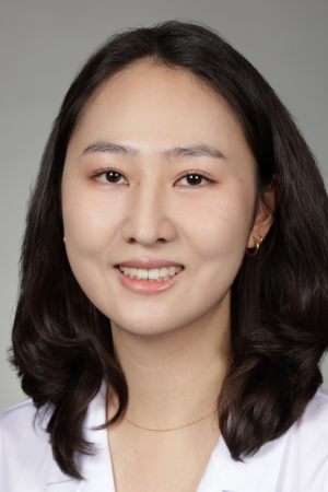 Portrait of medical student Aileen Kimm in white coat and smiling.