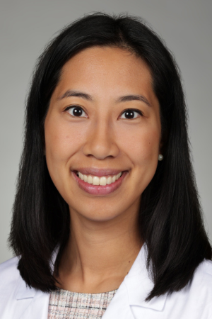 Portrait of medical student Charlotte Zhang in white coat and smiling.