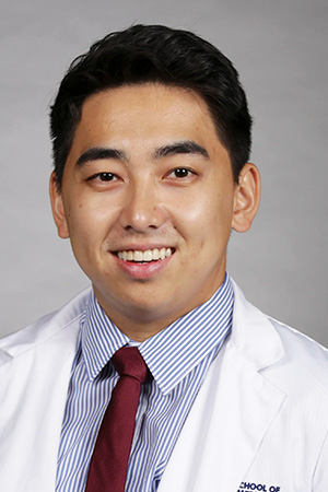 Portrait of medical student Aaron Vang in white coat and smiling