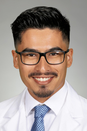 Portrait of medical student Jose Aguilar in white coat and smiling